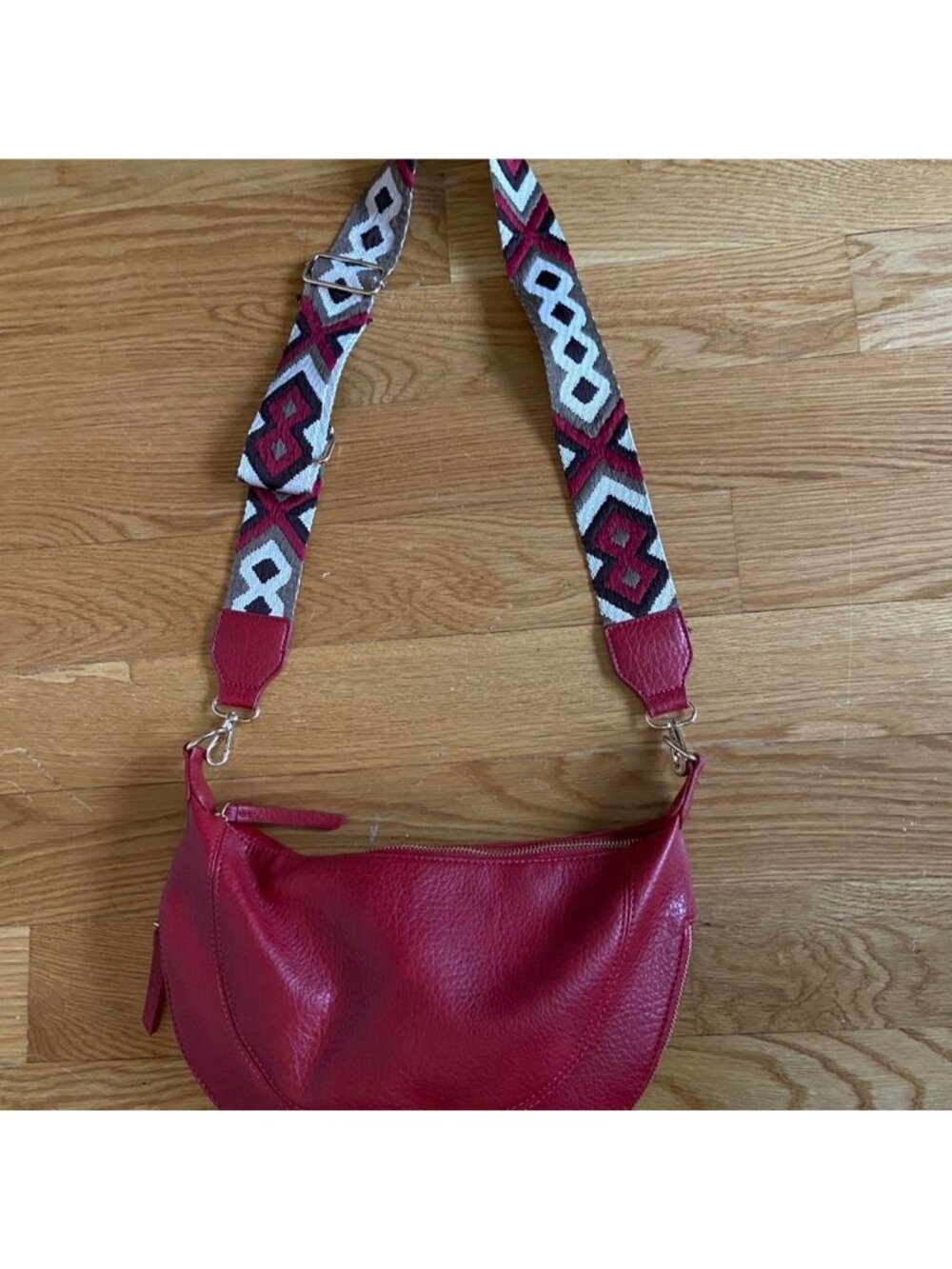 Burgundy crossbody bag with gold hardware and patterned adjustable strap